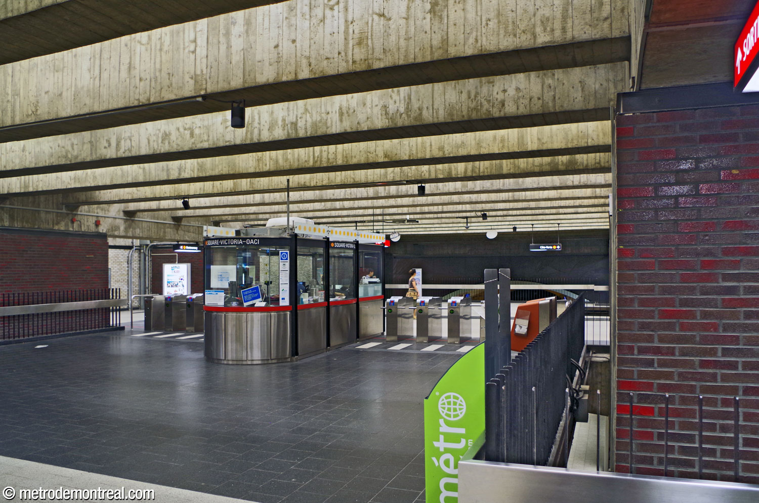 Vue de la mezzanine et de la zone contrôlée. Des grilles parcourent tout le pourtour de la billetterie, protégeant des percées visuelles étroites qui soulignent que cet espace est aménagé sur une mezzanine au-dessus des quais.