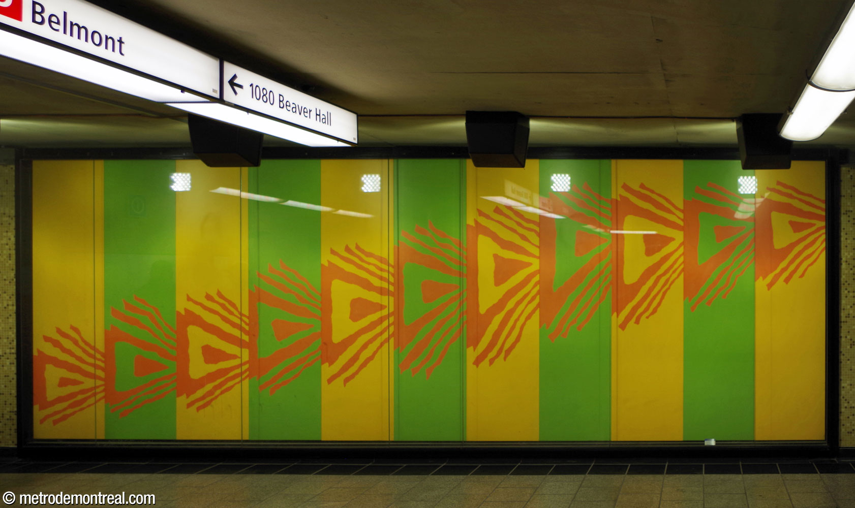 Les coloris brillants de la murale en plastique laminée de Jean-Paul Mousseau, située au niveau du palier sous l'entrée Belmont. Les flèches orange indiquent le chemin à suivre vers la station.