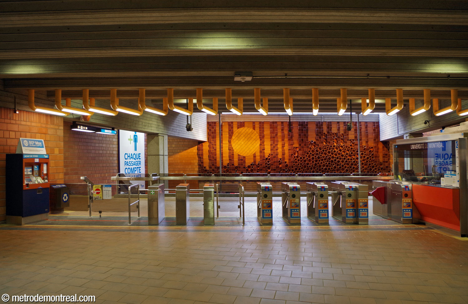 La loge et la barrière de perception au niveau de la mezzanine. Au fond, la plus grande des deux sculptures murales en terre cuite, œuvres de l'architecte de la station, André Léonard, surplombe le volume au-dessus des quais.