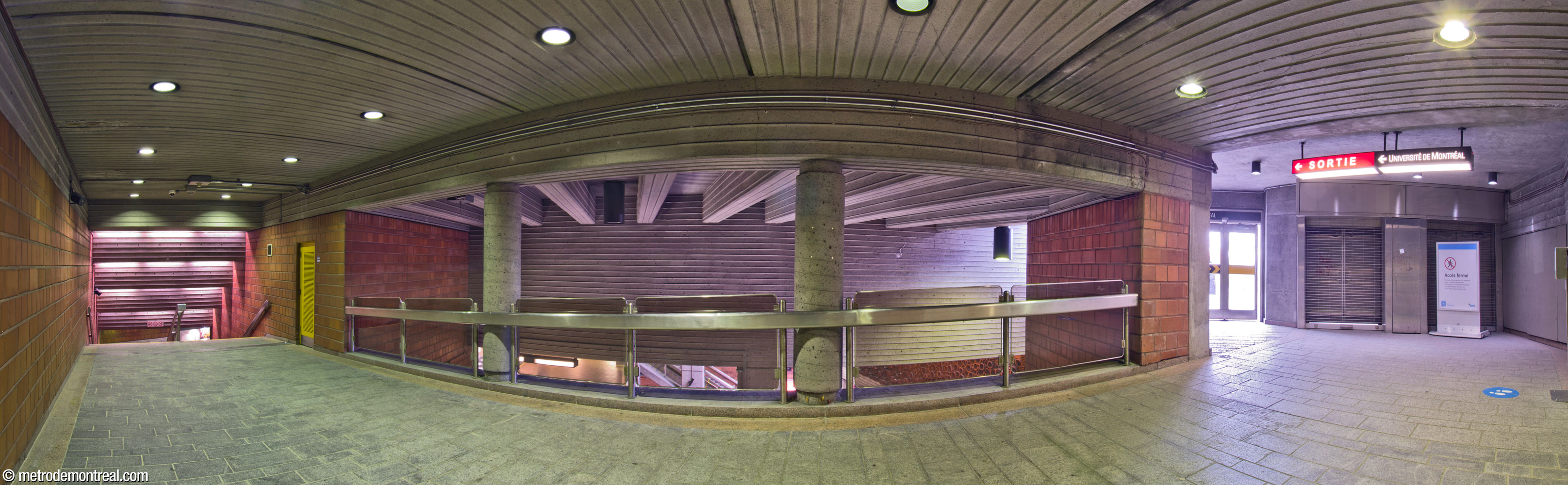 Intérieur de la sortie vers le Tunnel de la Montagne et le campus de l’Université de Montréal. Ce couloir passe en haut et au sud du grand volume au-dessus de la billetterie et des quais en contrebas (centre). À droite, près de la sortie, un accès intérieur direct vers le Tunnel de la Montagne a été aménagé, mais demeure fermé à cause de problèmes techniques en lien avec les courants d’air générés par le passage des rames de métro.