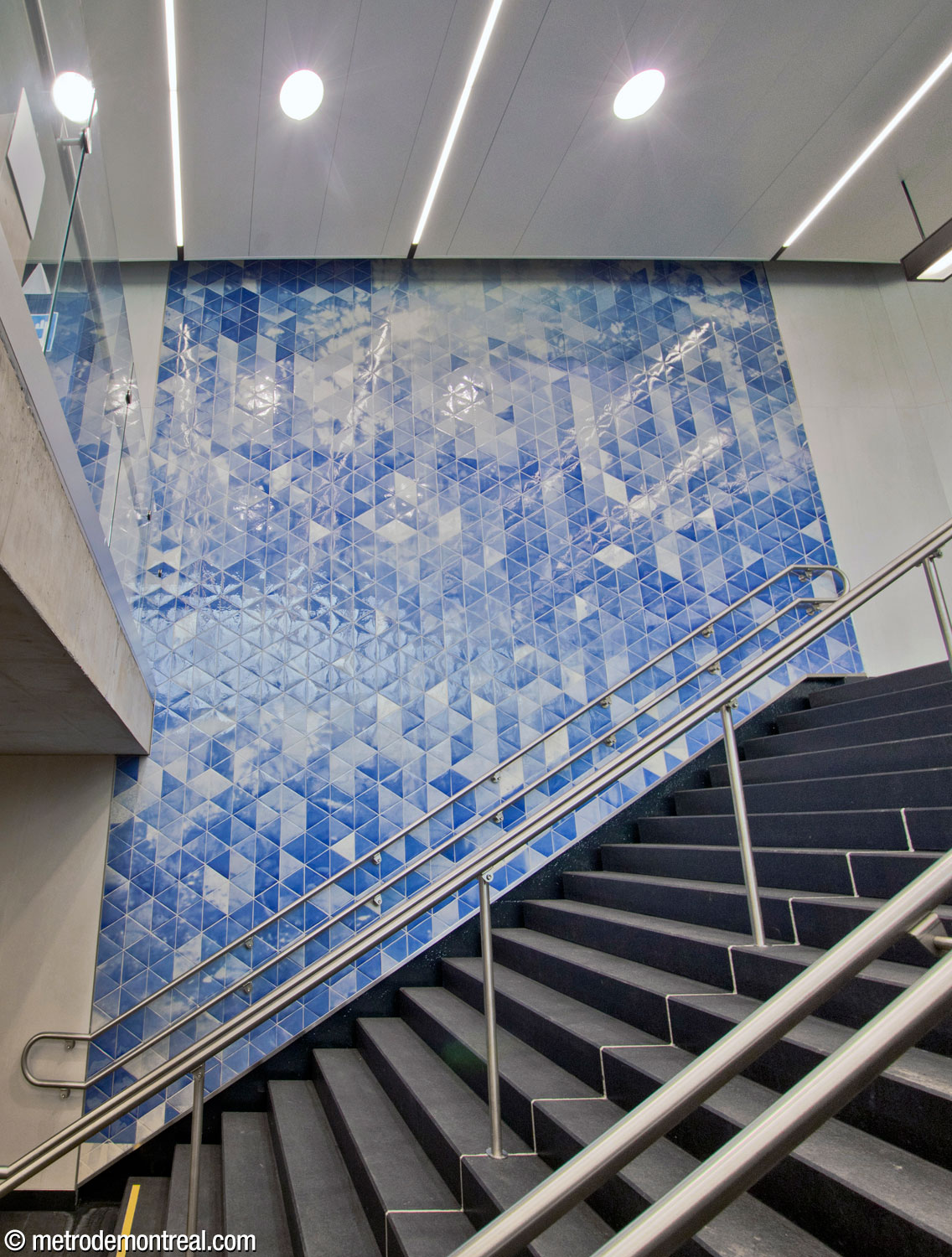 The first section of Patrick Bernatchez's mural cycle Bleus sténopés : de l’atelier à la station Vendôme, le 8 septembre 2019, located in the secondary headhouse above the stairs to the Côte-Vertu platform.