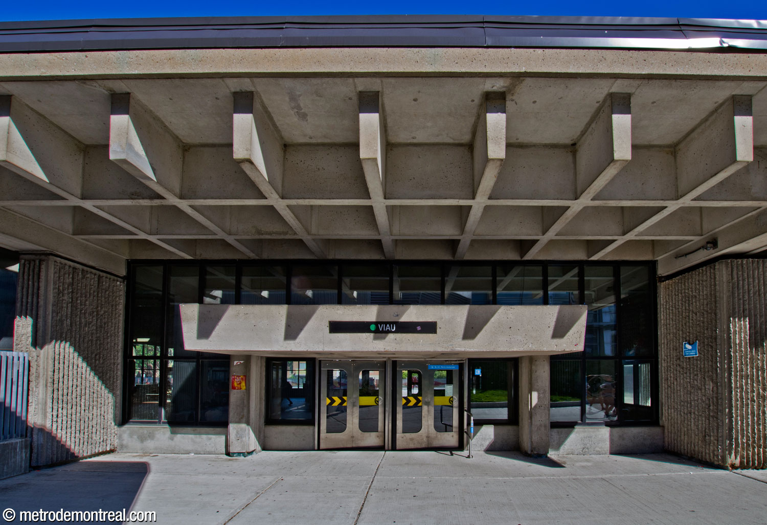 Front view of the station's north entrance. The doorway is emphasized by an imposing awning, despite also being below the broad roof projection. Note the exposed ends of the beams that form the roof’s coffers.