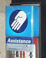A blue hand symbol indicating an assistance point on a station platform