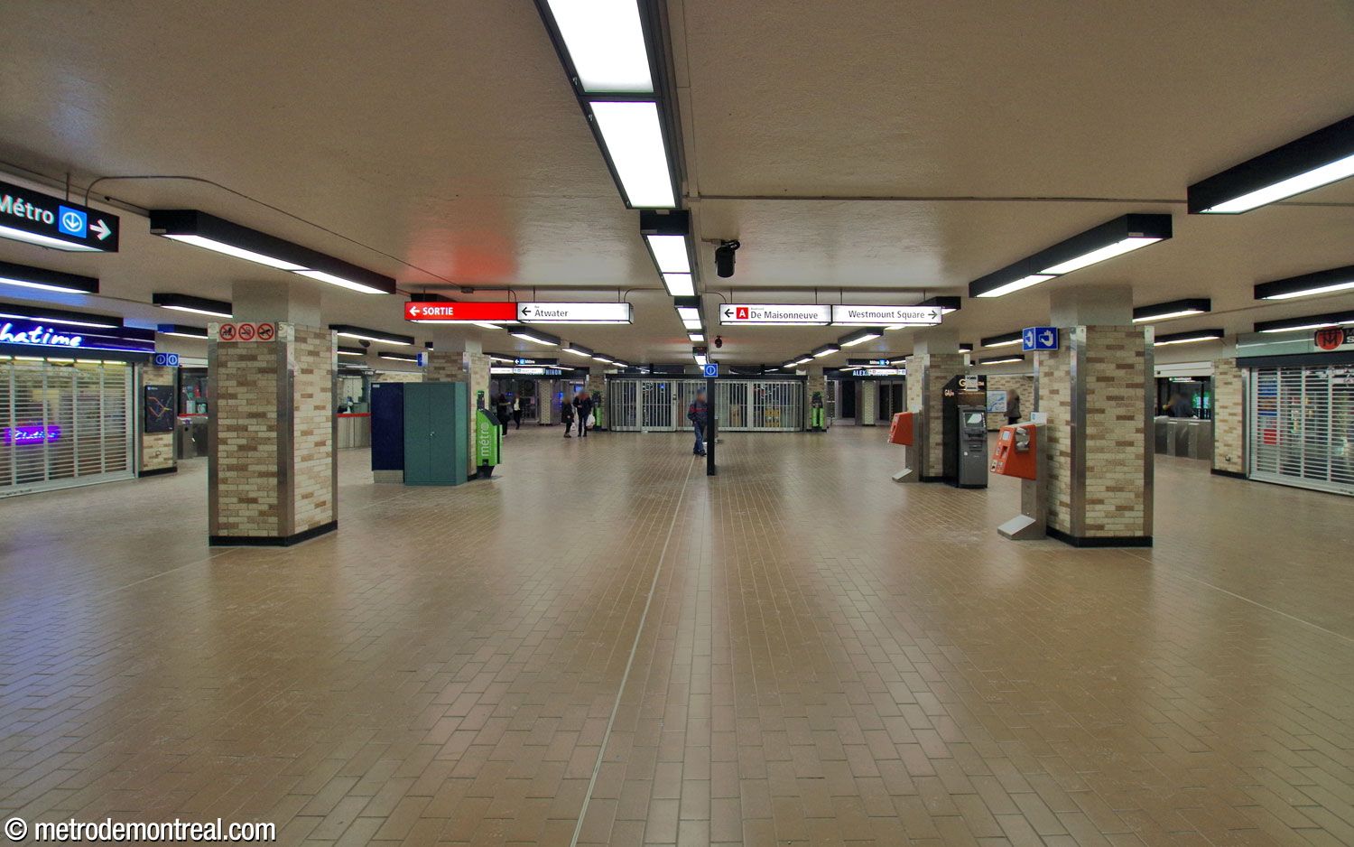The ticket hall concourse prior to the installation of elevators. At the south end of the hall (background), the concession is located at the centre, between two entrances to Complexe Alexis Nihon. Today, the elevator to the Honoré-Beaugrand platform is located where the right-hand entrance is in this photo, and the entrance to the shopping centre was moved to the centre, with a new concession space at left. The fare-paid zone for the Angrignon elevator is located in the space framed by the two columns in the foreground at left.