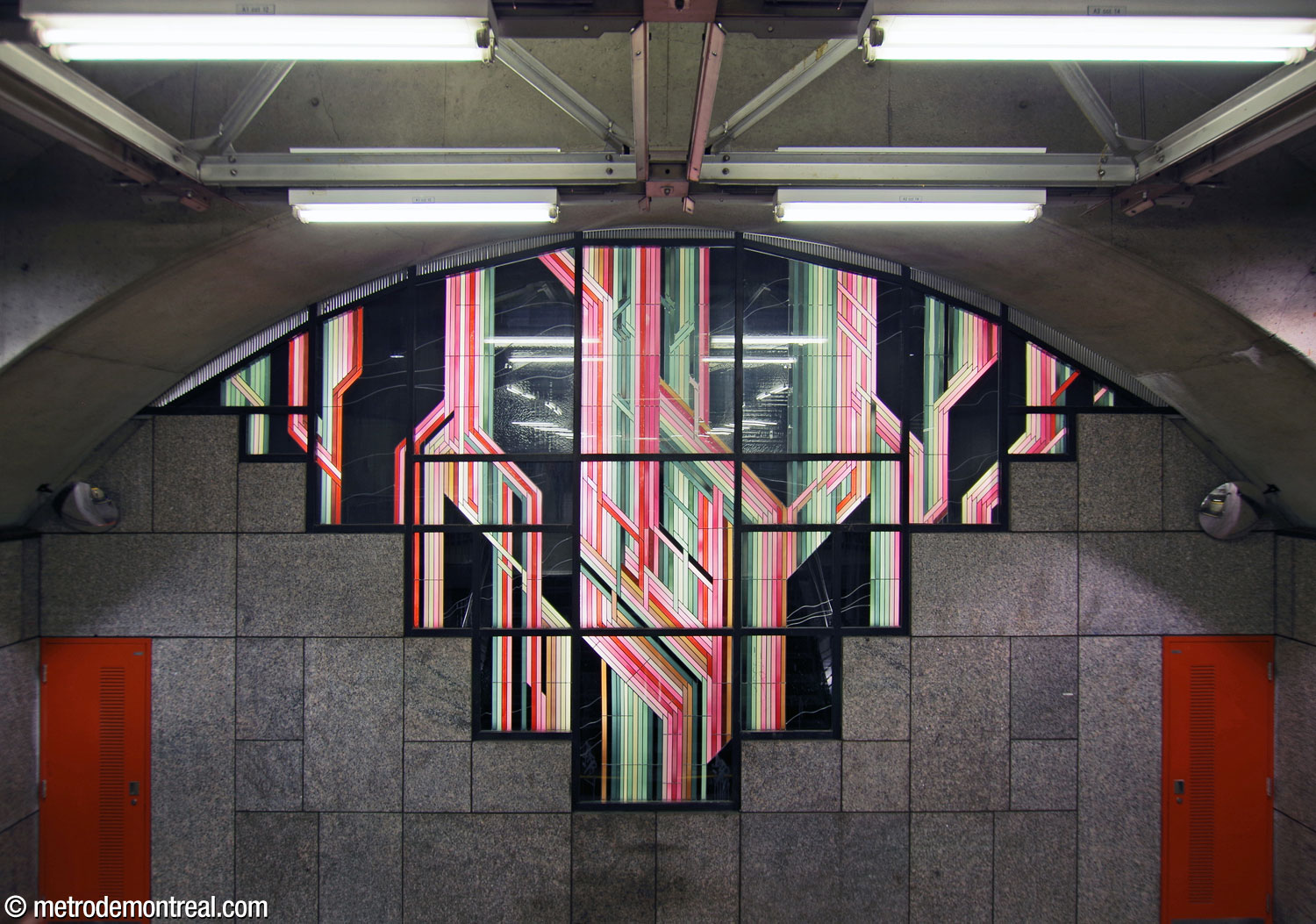 The large backlit stained glass work by Claude Bettinger over the stairs to the Snowdon platform, at the end of the transept/ticket hall tunnel. The impressive work features a 'cybernetic' interlace of bundles of pink, white, and cyan stripes on a black background.