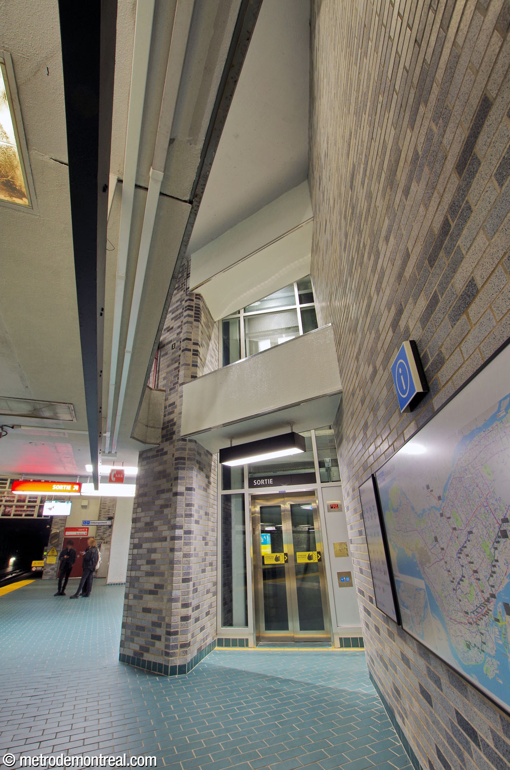 The elevator shaft from the Angrignon platform up to the walkway level. The glass shafts are visible from the platform, and are each partially integrated into one of the wall zigzags.