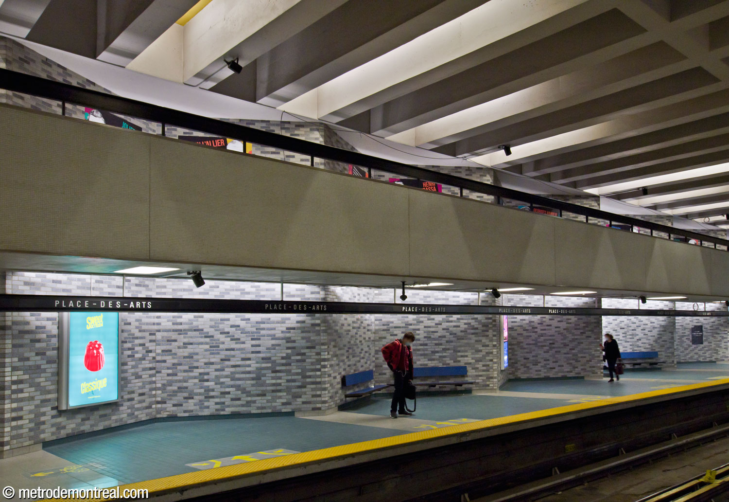 The zigzagging wall along the Angrignon platform, with one of the twinned walkways overhead.