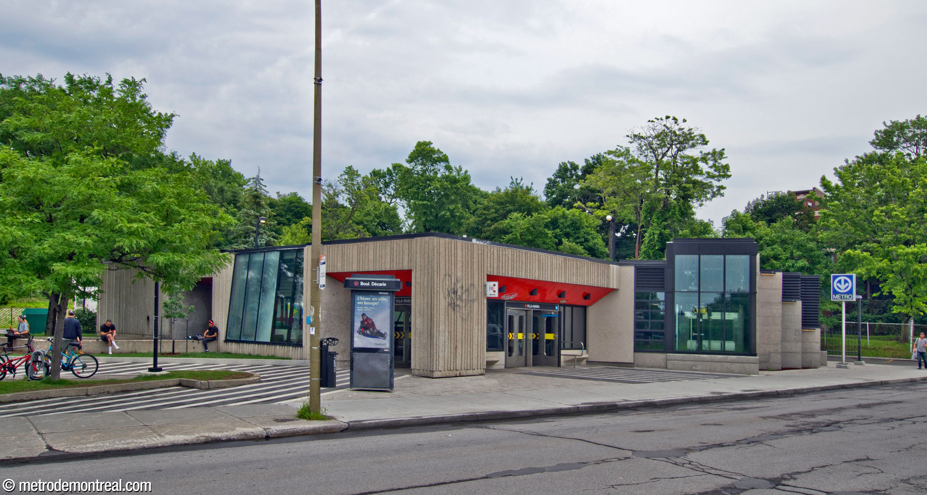 L'édicule de la station vu du nord-ouest. On voit les entrées et les baies vitrées enfoncées dans la façade de béton.